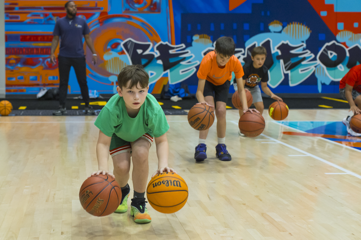 Young athlete in a green shirt working on a two-ball dribbling drill.