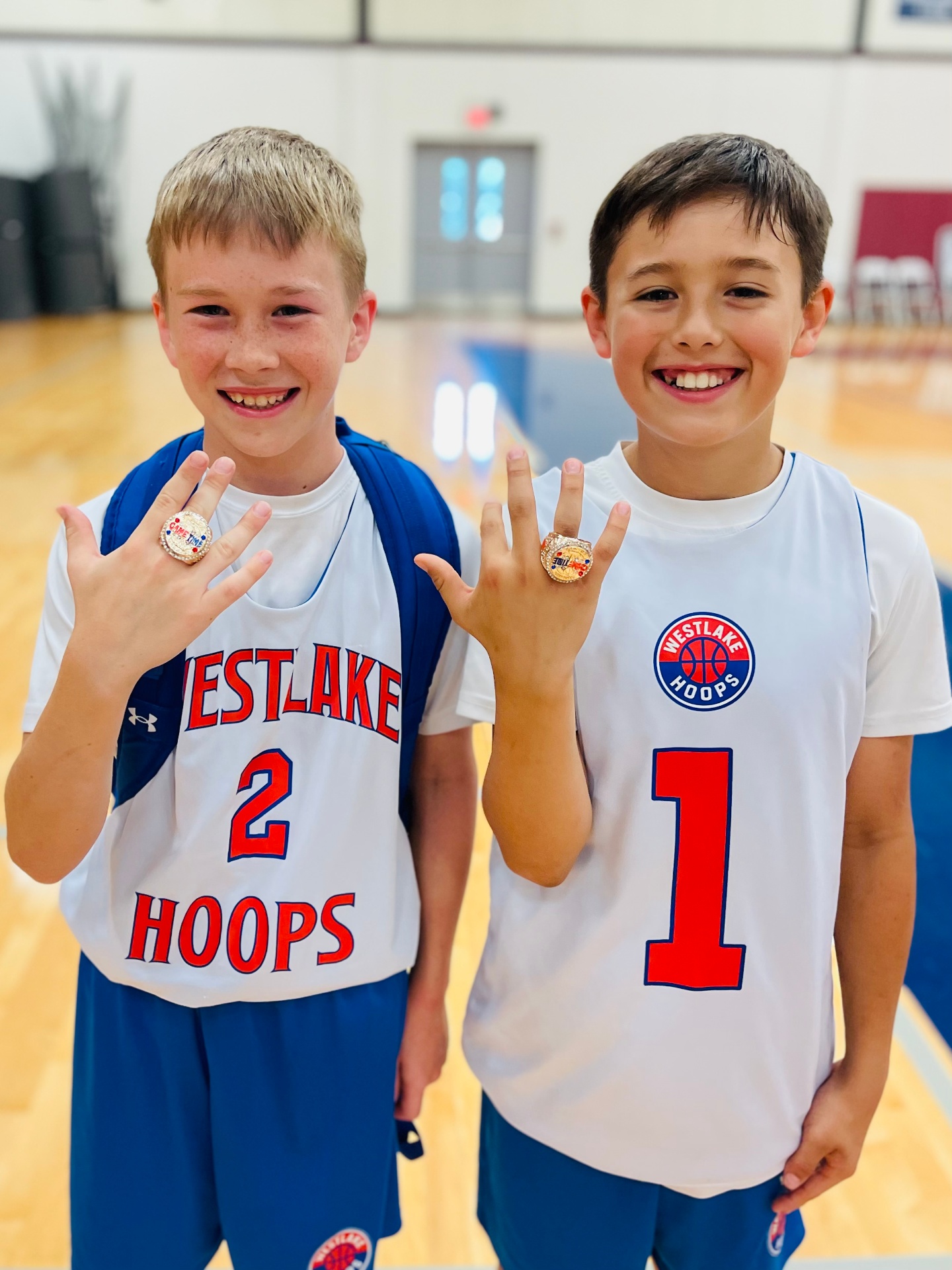 Two Westlake Hoops players showing off their championship rings courtside.