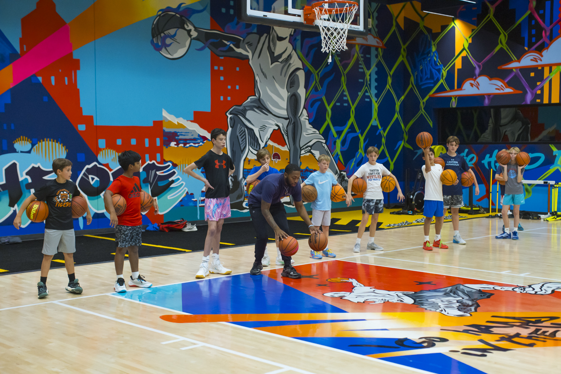 Coach leading a group dribbling drill under the hoop.