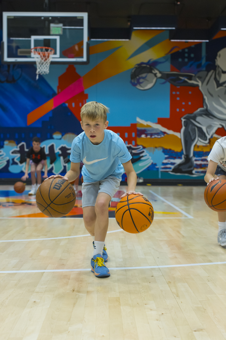 Athlete in a light blue shirt running a two-ball crossover drill.